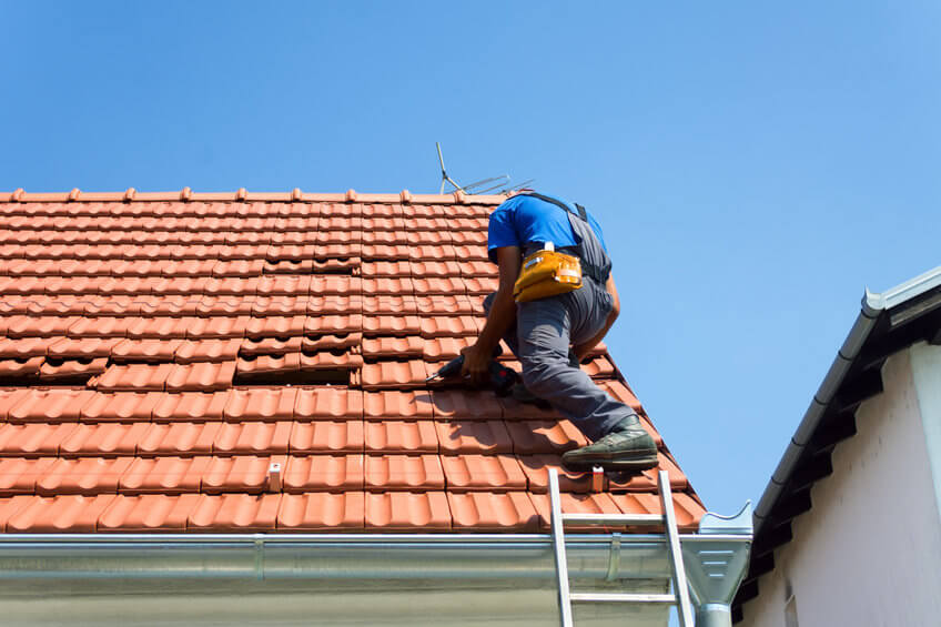 a technician repairs a damaged tile roof